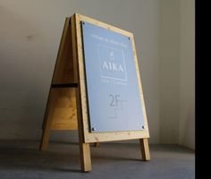 a wooden sign sitting on top of a floor next to a white wall and cement floor