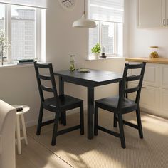 a kitchen table with two chairs and a clock on the wall in front of it