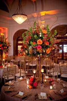 an elegant centerpiece with flowers and greenery is displayed on a round dining table