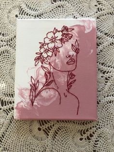 a pink and white square with a drawing of a woman's face on it