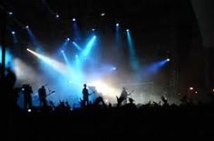 a concert with blue and green lights on the stage as well as people standing in front of them