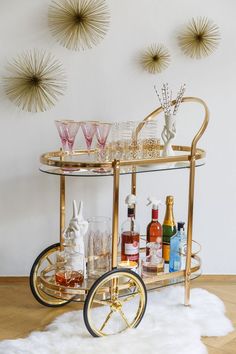 a gold bar cart filled with bottles and glasses