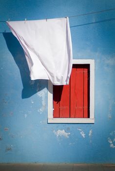 a blue wall with a red door and white sheet hanging from it's side