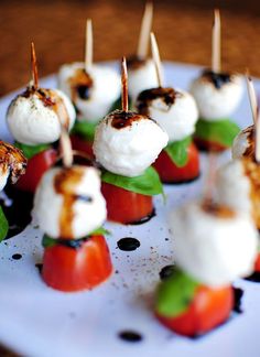 small appetizers with toothpicks and tomatoes on a white plate