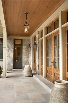 an image of a porch with stone pillars and doors on the side walk, along with a lantern light