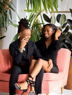 two women sitting on a pink couch next to each other