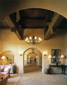 an archway leading to a living room with chandelier and lamps on either side