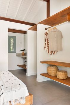 a bedroom with white walls and wooden shelves