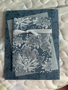 two folded cards on top of each other with blue and white floral designs in them