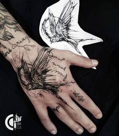 a person's hand with tattoos on it and a bird in the sky above them