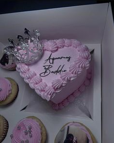 a pink heart shaped cake in a box with cupcakes on the side and a tiara