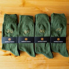 five pairs of green socks with gold lettering on them sitting on a wooden table top