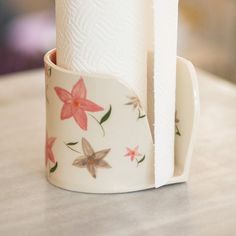 two rolls of toilet paper sitting on top of each other in a cup with flowers painted on it