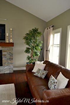 a living room with a brown leather couch and television on the fireplace mantels