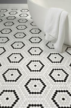 a bath tub sitting next to a white and black tiled floor