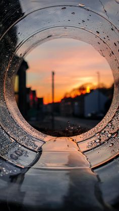 the inside of a metal object with water droplets on it at sunset or dawn in the city