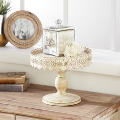 there is a small white box on top of a cake stand in front of a window