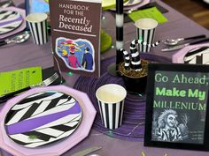 the table is set up with purple and black striped plates, napkins, and other items