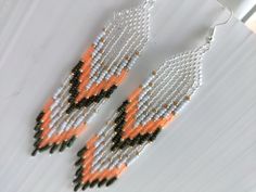 an orange and white beaded earrings hanging from a hook