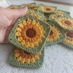 a hand is holding four crocheted coasters with sunflower designs on them