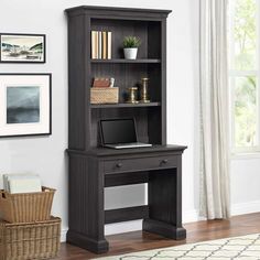 a desk with a laptop on top of it in front of a bookcase and window