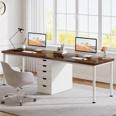 a desk with two computer monitors on top of it next to a chair and window