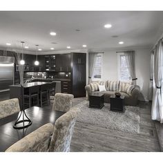 a living room filled with furniture next to a kitchen and dining room table in front of a stove top oven