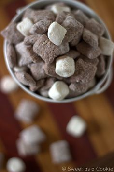 a bowl filled with chocolate and marshmallows on top of a wooden table