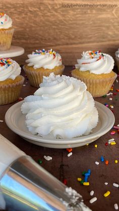 cupcakes with white frosting and sprinkles on a table