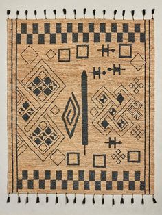 an area rug with black and white designs on the side, fringes hanging from it