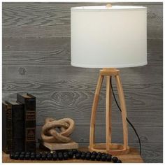 a wooden table lamp sitting on top of a book shelf next to a pile of books