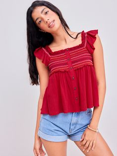 a woman wearing a red top and denim shorts Casual Red Cotton Smocked Top, Trendy Red Top With Ruffles, Red Casual Smocked Top With Ruffles, Red Smocked Top With Ruffles For Summer, Spring Red Smocked Top With Ruffles, Casual Red Smocked Top For Fall, Red Cotton Smocked Fitted Top, Red Fitted Cotton Smocked Top, Fitted Red Cotton Smocked Top