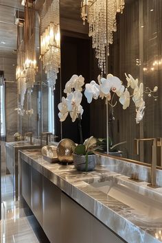 a bathroom with two sinks and chandeliers hanging from the ceiling