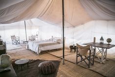 a large tent with two beds and chairs in the room next to eachother