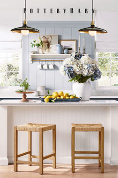 two stools sit in front of a bar with flowers and lemons on it