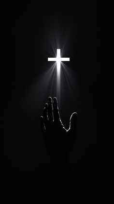 a person holding their hands up in the dark with a cross on top of them