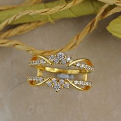 two gold rings with diamonds on them sitting next to some dried grass and leaves in the background