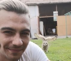 a man is taking a selfie in front of a barn with an animal behind him