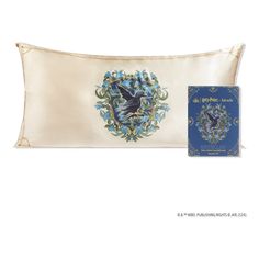 an embroidered pillow with a blue and white bird on it next to a boxed book