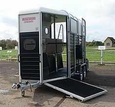 a horse trailer is parked in the dirt