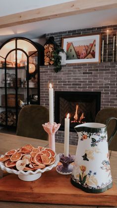 a wooden table topped with plates of food and a tea kettle next to a fireplace