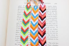 two colorful chevron bracelets on top of an open book, one with a tassel hanging from it