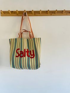 a tote bag hanging on a coat rack with the word sorry written in red