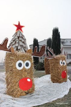 two hay wrapped reindeer heads sitting on top of a white cloth covered ground next to a christmas tree