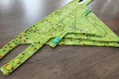 two pieces of green fabric sitting on top of a wooden table