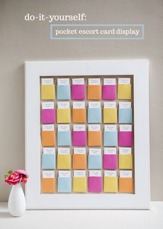 a white vase with a pink flower in it next to a colorful sticky note board