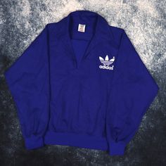 "Details: Vintage blue training sweatshirt by Adidas. White trefoil logo printed on the front and back. Condition: Good Signs of wear: N/A Size: XS Measurements: Length - 23.5\" Pit to Pit - 21\" Shoulder to cuff - 22\"" Blue Logo Sweatshirt For Streetwear, Blue Cotton Sweatshirt With Logo, Long Sleeve Logo Tops In Athleisure Style, Athleisure Long Sleeve Tops With Logo, Sporty Logo Tops For College, Casual Blue Sweatshirt With Logo, Sporty Logo Top For Sports Events, Sporty Tops With Logo For Sports Season, Sporty Blue Tops With Logo