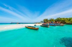 several boats are parked on the beach in clear blue water