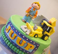 a birthday cake with a construction theme and a small figure on top that says up