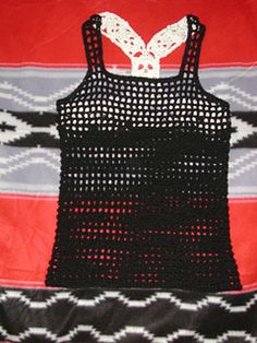 a black and red top with white crochet on the front, sitting on a blanket